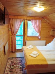 a bedroom with a bed and two windows with towels at Casa Arion in Arieşeni +37 photos