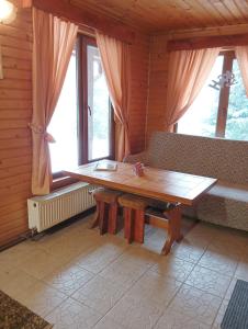 a wooden table and bench in a room with windows at Casa Arion in Arieşeni