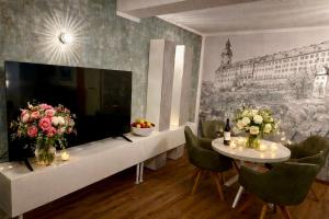 a room with a large tv and a table with flowers at AltstadtQuartier Rudolstadt Ankommen l Bleiben in Rudolstadt