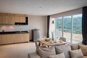 a living room with a couch and a table and a kitchen at Santosa Hotel & Welness Center in Kata Beach