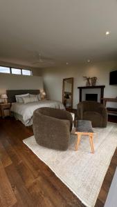 a bedroom with a bed and two couches and a table at Waiheke Luxury Blue and Green Rooms in Ostend