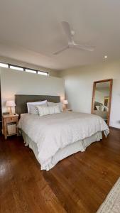 a bedroom with a large bed with a ceiling fan at Waiheke Luxury Blue and Green Rooms in Ostend