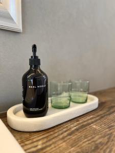 a bottle of soap and two glasses on a counter at Waiheke Luxury Blue and Green Rooms in Ostend