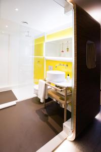 a bathroom with a white sink and yellow walls at The Corner London City in London