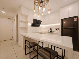a kitchen with a large white counter and stools at Sunway Onsen Suites - Theme Park Tambun Ipoh by Ryokan Management in Tambun