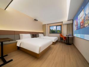 a hotel room with two beds and a tv at The Screen Hotel Hangzhou East St ation-Zhanongkou Metro in Hangzhou