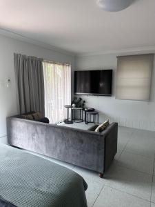 a living room with a couch and a tv at Mediterranean Studio & Garden View Private Pet Friendly in Brisbane