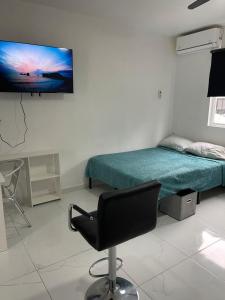 a room with a bed and a chair and a monitor on the wall at Consulado Santa Catarina a 2 min in Monterrey