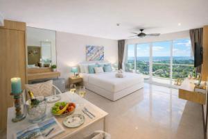 a bedroom with a white bed and a large window at Santosa Hotel & Welness Center in Kata Beach +33 photos