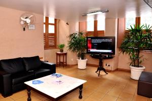 a living room with a couch and a tv and plants at Hotel Plaza Riazor in Rio de Janeiro