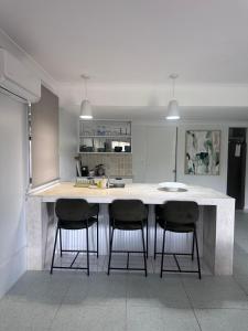 a kitchen with a large white island with three bar stools at Mediterranean Studio & Garden View Private Pet Friendly in Brisbane