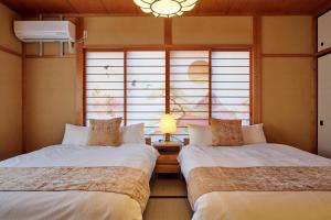 two beds in a room with a window at R STAY Nagoya Atsuta in Nagoya