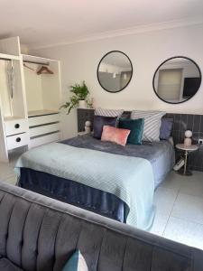 a bedroom with a large bed with two mirrors on the wall at Mediterranean Studio & Garden View Private Pet Friendly in Brisbane