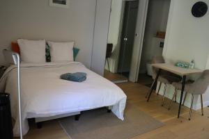 a bedroom with a white bed with a table and a tableablish at Studio for 2 people in Bouloc