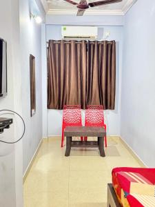 a room with two red chairs and a bench in front of a window at Saichha Guest House in Calangute +15 photos