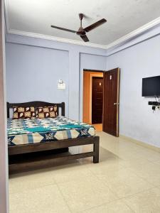 a bedroom with a bed with a ceiling fan at Saichha Guest House in Calangute