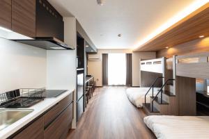 a room with two bunk beds and a kitchen with a sink at ReLA Kashiwa Eki Mae in Kashiwa