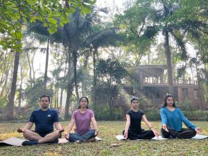 a group of people sitting in a yoga pose at Aayush Resort Karjat in Kālundri