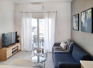 a living room with a blue couch and a tv at Blue wave in Ierapetra
