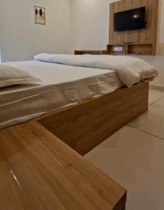 a bed with a wooden frame with a tv on the wall at Grand UNX in Kannur