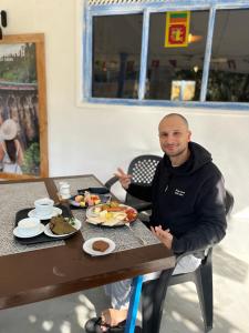 a man sitting at a table with a plate of food at Ella Ceylon Homies Hostel in Ella