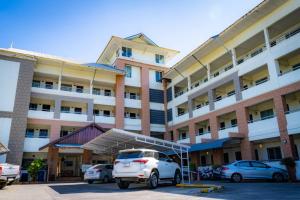 a white car parked in front of a large building at Saksiri apartment in Ban Si Than