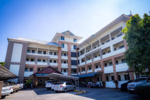 a large building with cars parked in a parking lot at Saksiri apartment in Ban Si Than