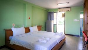 a bedroom with a large white bed with white bows at Saksiri apartment in Ban Si Than