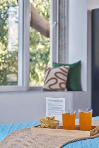 a tray with two glasses of orange juice on a table at SaffronStays Indigo House in Karjat