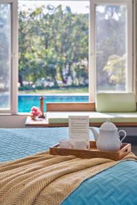a tray with a tea pot on top of a bed at SaffronStays Indigo House in Karjat