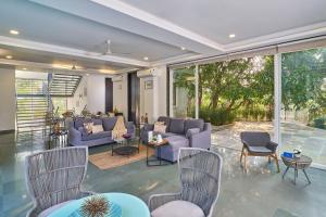 a living room with purple couches and chairs at SaffronStays Indigo House in Karjat