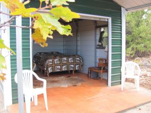 a room with a bed and two chairs on a porch at Lupine Cabin, Glamour Camping, Stunning Skies and Sunrise Views in Monticello
