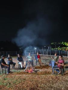 a group of people sitting around a fire at night at Lagoon celebration10 in Perumanseri +3 photos