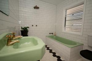 a bathroom with a green sink and a tub at Herbgully Cottage in Roma