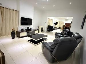 a living room with black leather chairs and a flat screen tv at Lonehill Ridge in Blantyre