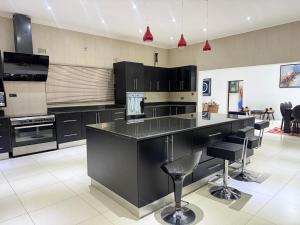 a large kitchen with black cabinets and bar stools at Lonehill Ridge in Blantyre