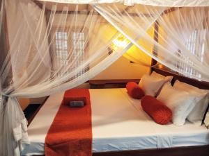 a bed with red and white pillows and a canopy at Subhasha Summer House in Talalla South