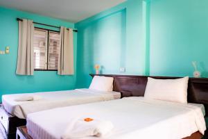 two beds in a room with blue walls at Saksiri apartment in Ban Si Than +27 photos