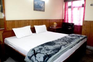 a bedroom with a bed and a table with a chair at Hotel Lhakhar in Gangtok