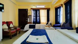 a hotel room with two beds and a chair at Hotel Orchid in Kalimpong