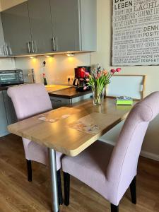 a kitchen with a wooden table with purple chairs at Premium Apartment-OstseePur-inklusive Parkplatz-Wlan-Strand-und Citynähe in Timmendorfer Strand