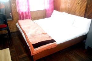 a bed with a blanket on it in a room at Hotel Lhakhar in Gangtok