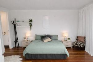 a white bedroom with a bed and a chair at Blagdon Close Guesthouse in New Plymouth