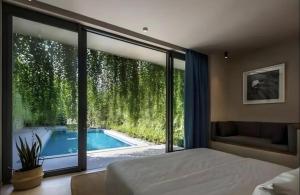 a bedroom with a view of a swimming pool through a window at Hana Village Garden Tropical Bãi Khem in Phú Quốc