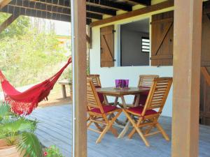 d'une terrasse avec une table, des chaises et un hamac. dans l'établissement Le Pic De La Buse, à Les Anses-d'Arlet