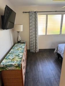 a small bedroom with a bed and a television at The Happy Hideaway - Maui Calm by the Ocean in Kihei