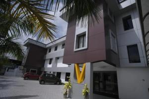 a building with cars parked in a parking lot at Veliyil Towers in Alleppey