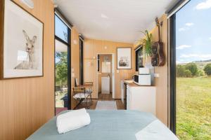 a room with a bed and a kitchen with a window at Kanimbla Sunsets by Tiny Away in Kanimbla