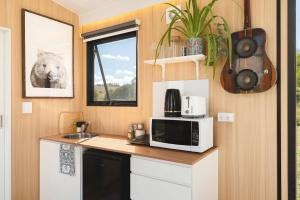 a small kitchen with a microwave and a sink at Kanimbla Sunsets by Tiny Away in Kanimbla