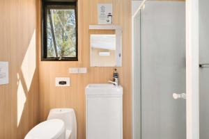 a bathroom with a toilet and a sink and a window at Kanimbla Sunsets by Tiny Away in Kanimbla